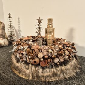 Hübsche Weihnachtsdeko mit Kerzen, Tannenzapfen, Baumkugeln und Zierteilen auf einem dekorativen Untergrund für festliche Stimmung.