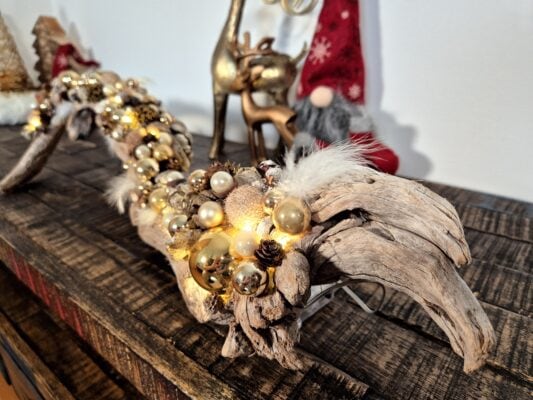 Goldfarbenes Treibholz mit Federn und Lichterkette