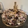 Goldener Adventskranz mit Tannenzapfen, Kerzen, Weihnachtskugeln, Rentier-Figur und Federn, festliche Weihnachtsdekoration, elegante kreative Tischdekoration, Winterzeit, Weihnachten.