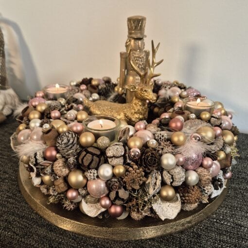 Goldener Adventskranz mit Tannenzapfen, Kerzen, Weihnachtskugeln, Rentier-Figur und Federn, festliche Weihnachtsdekoration, elegante kreative Tischdekoration, Winterzeit, Weihnachten.